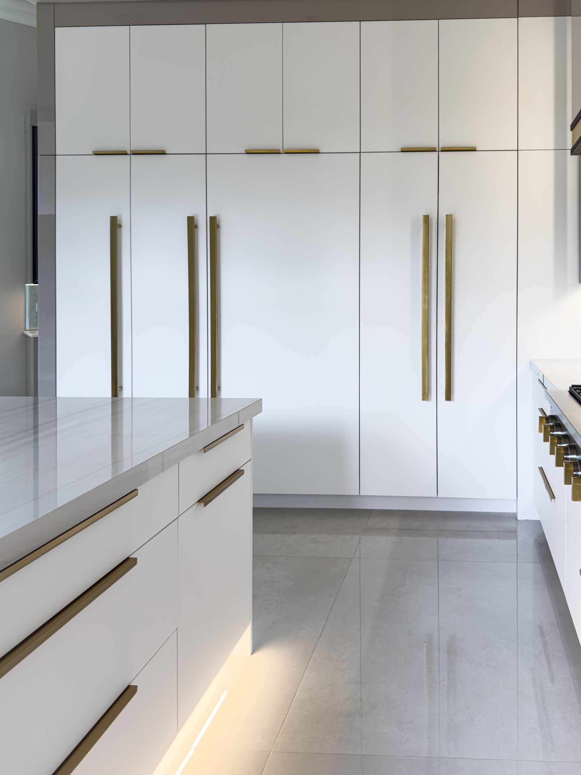 A kitchen with white cabinets , and a large island.