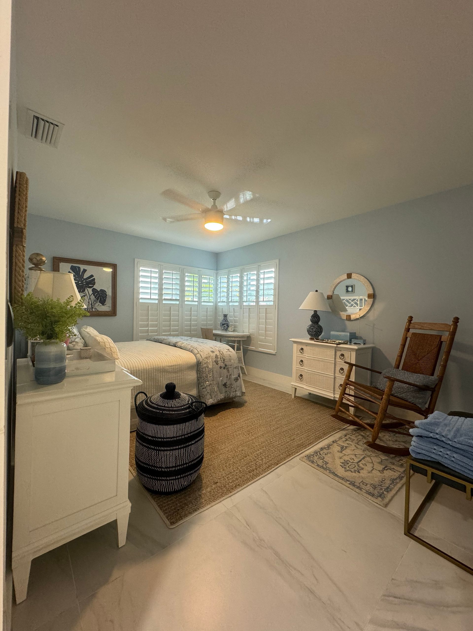 A bedroom with two beds , a rocking chair , a dresser and a mirror.