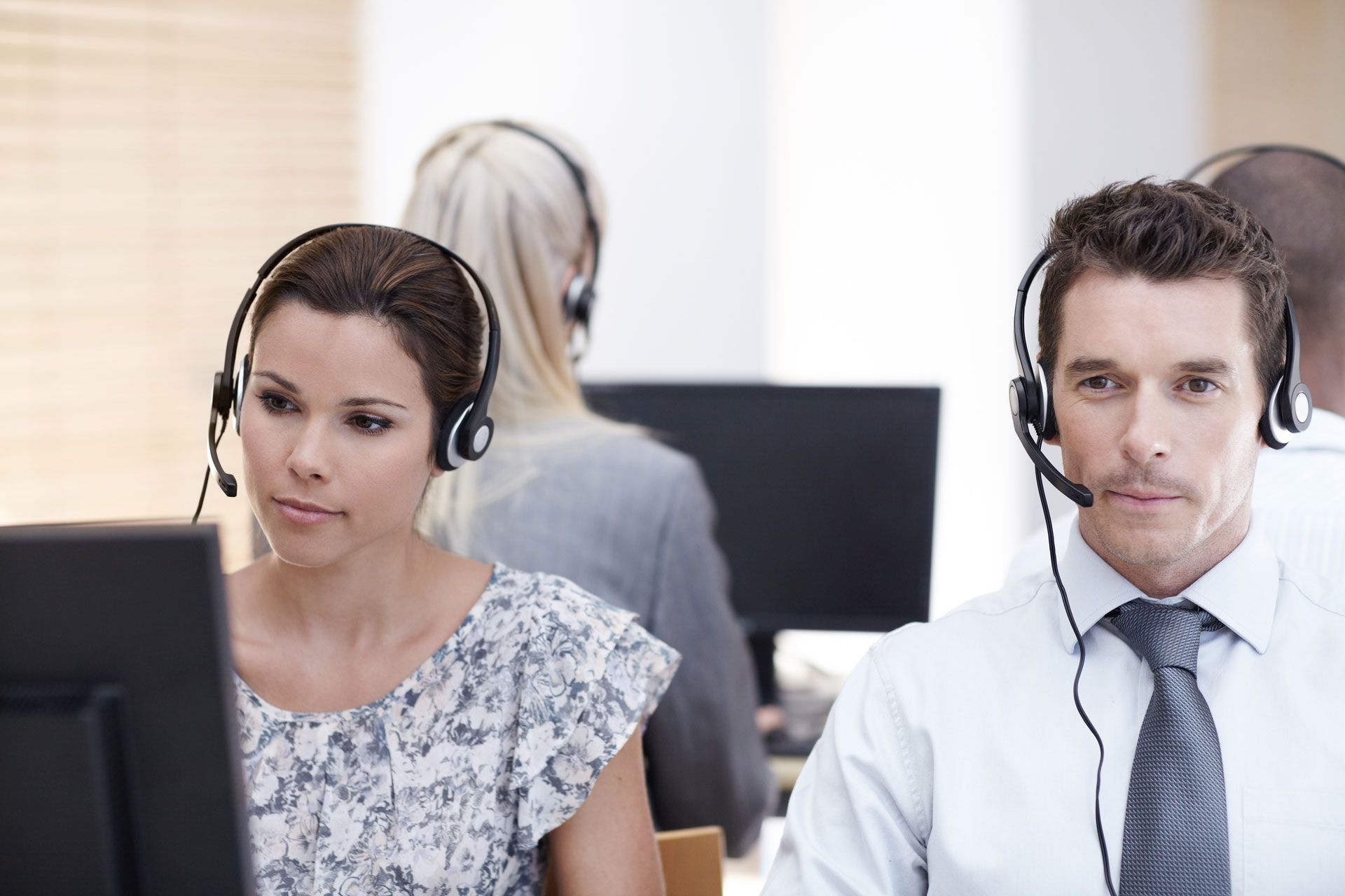 People wearing headsets, working at computers in an office setting.
