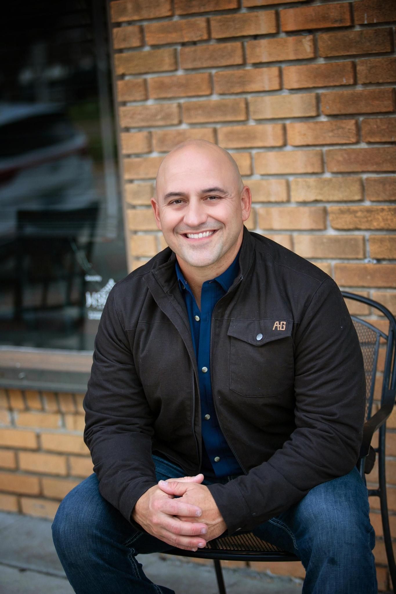 A man is sitting in a chair in front of a brick wall.