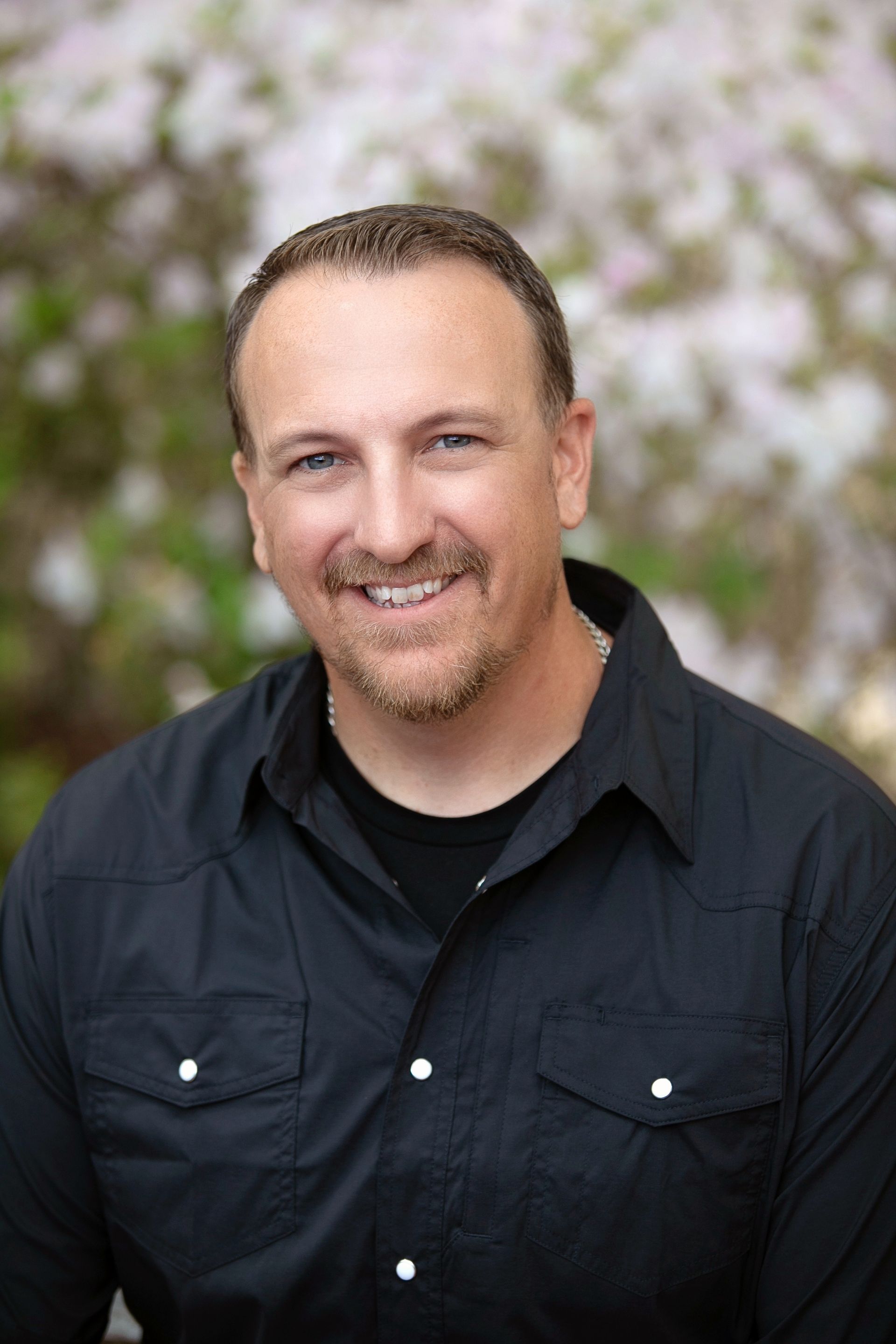 A man in a black shirt is smiling for the camera.