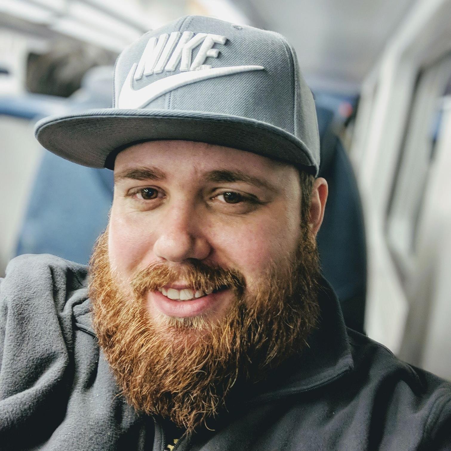 A man with a beard wearing a nike hat