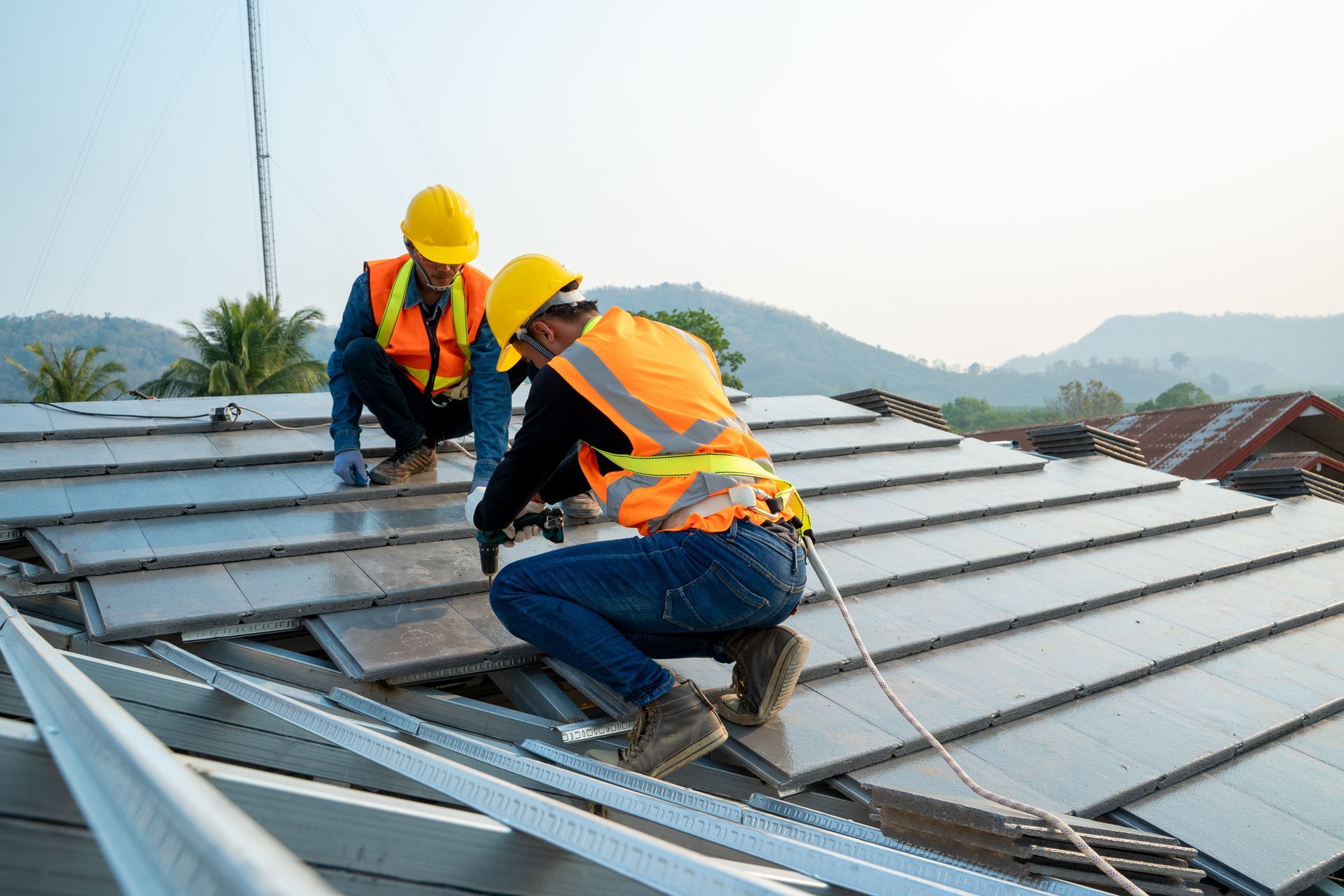 Roofing services team installing metal roof panels with safety gear on a residential building.