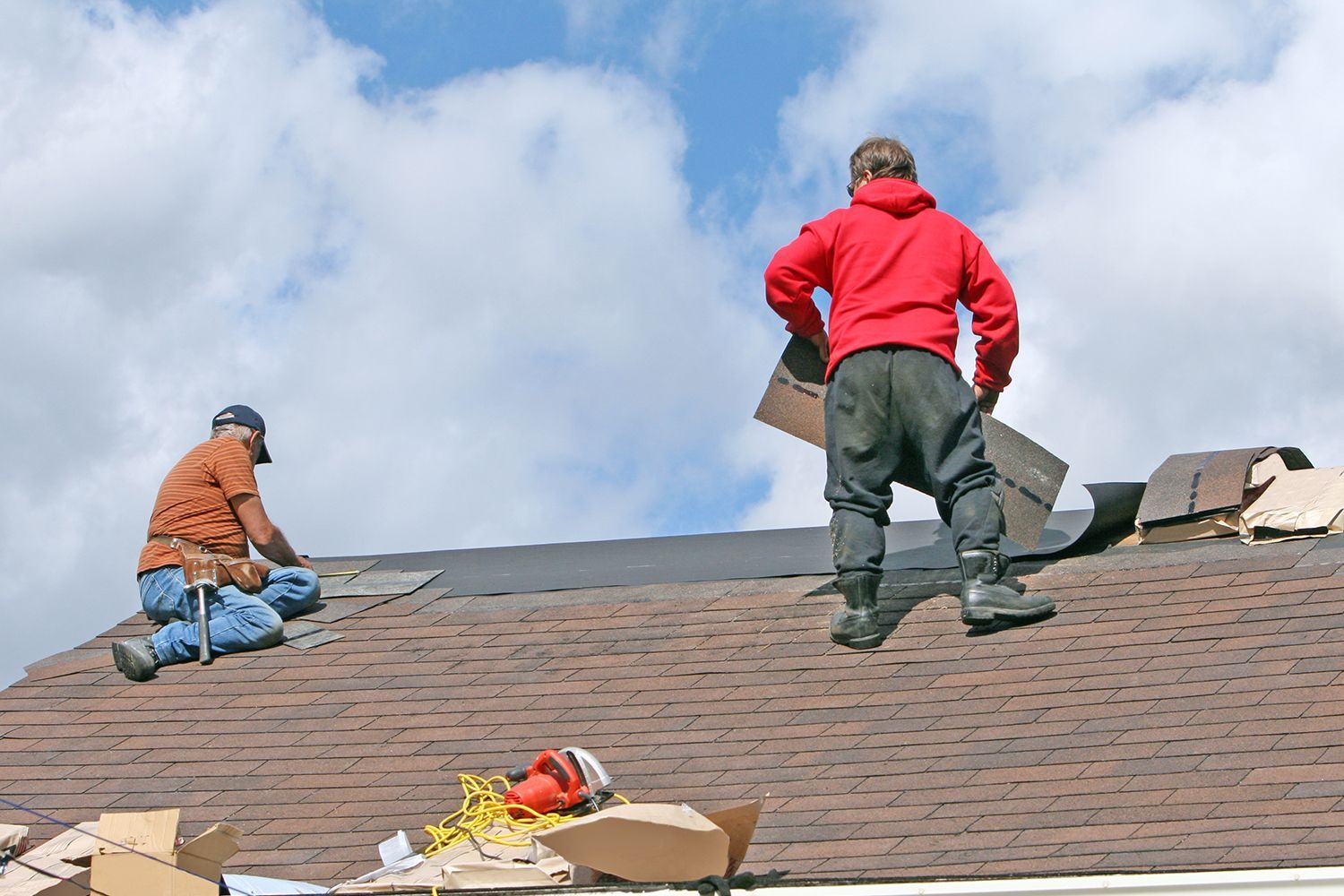Two professional male contractors completing roof repairs at a residential site.
