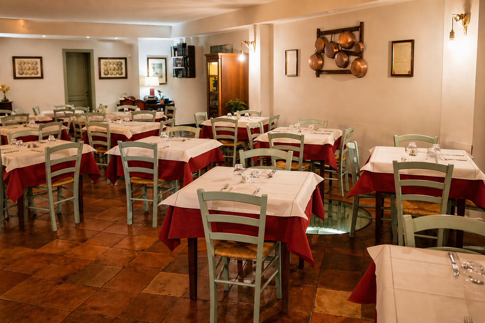 Sala da pranzo vuota di un ristorante, con tavoli apparecchiati con cura, tovaglie rosse e bianche e sedie di legno.