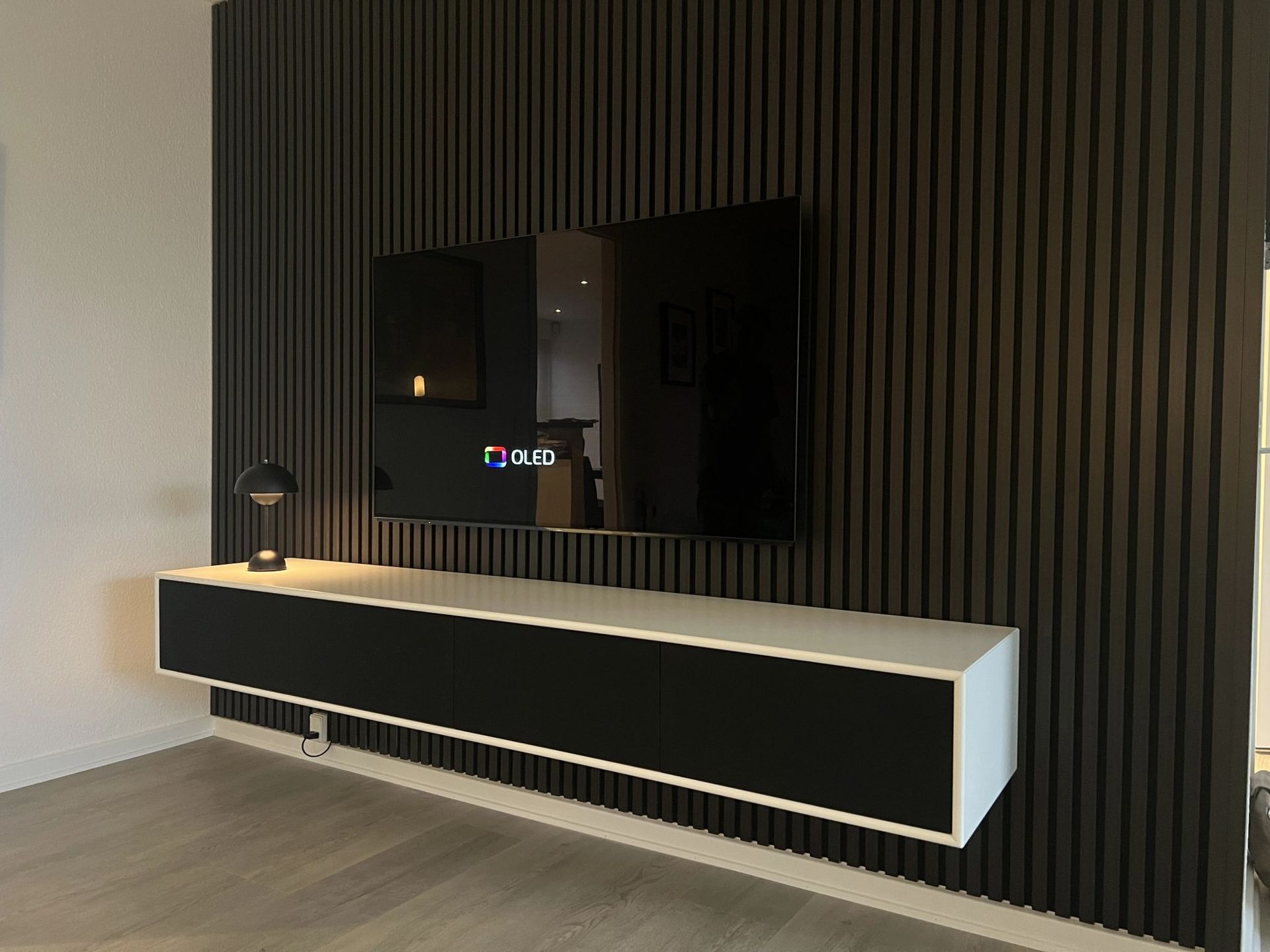 A living room with a flat screen tv and Frislev furniture mounted to the wall.