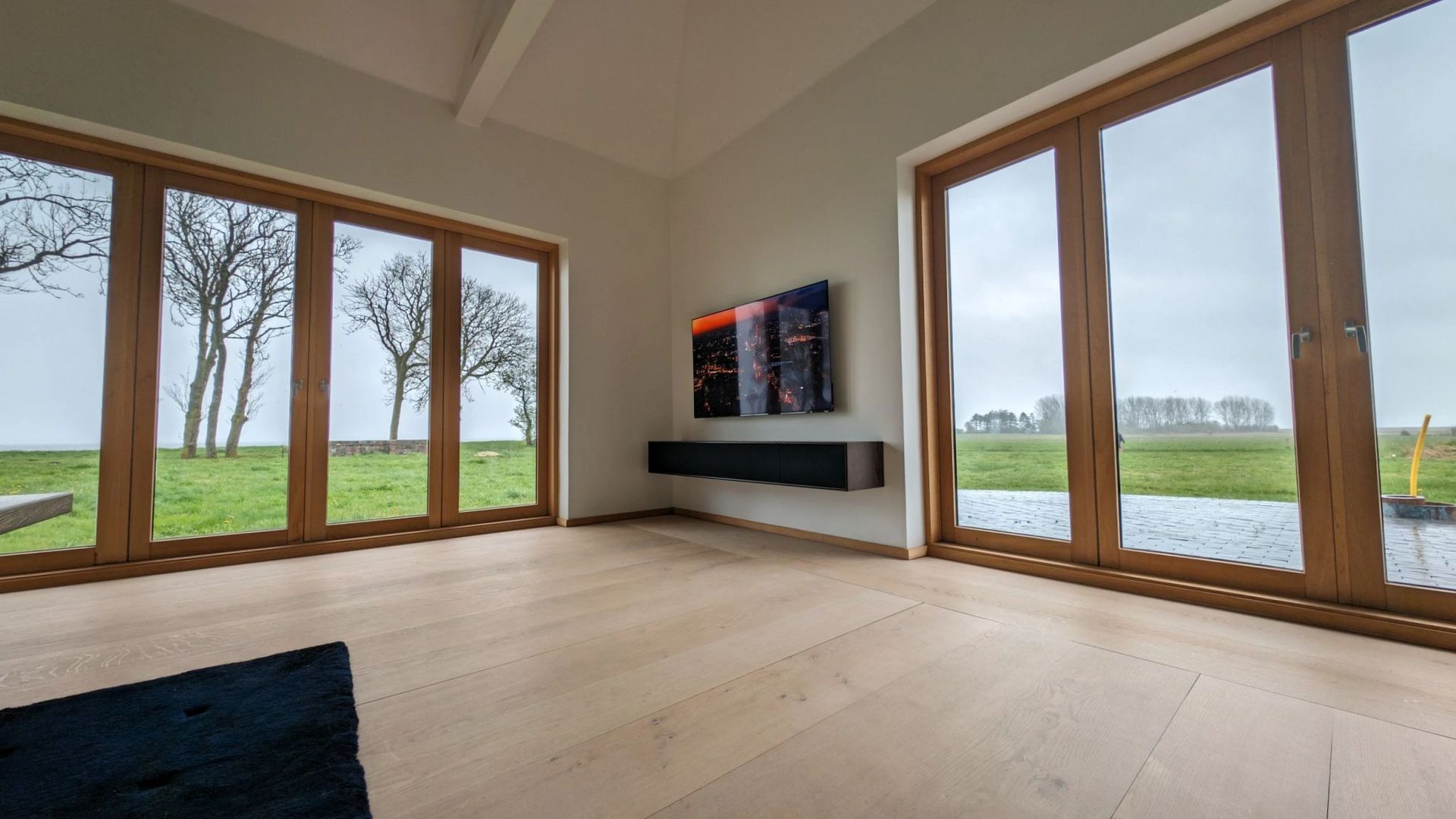 A living room with a lot of windows and a painting on the wall.