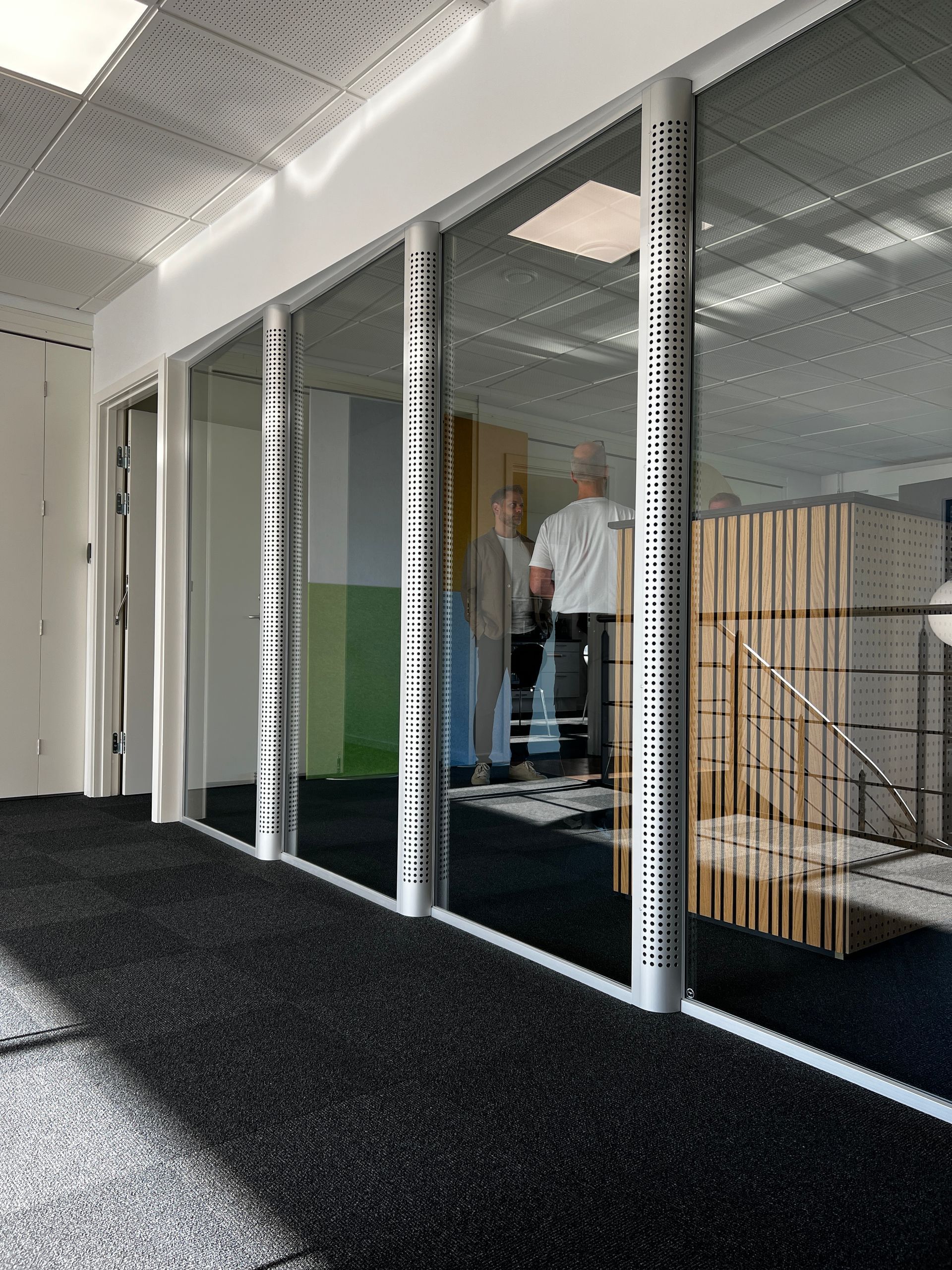 A hallway with glass walls and a black carpet