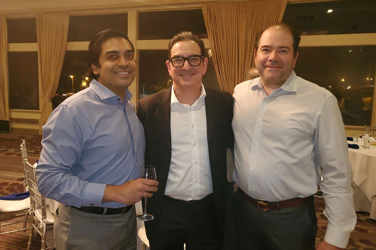 Three men are posing for a picture together in a room.