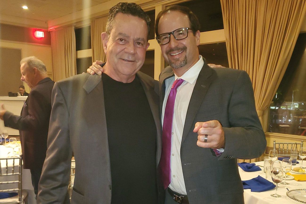 Two men in suits and ties pose for a picture