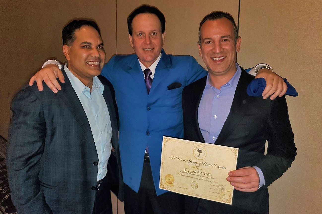 Three men are posing for a picture and one of them is holding a certificate