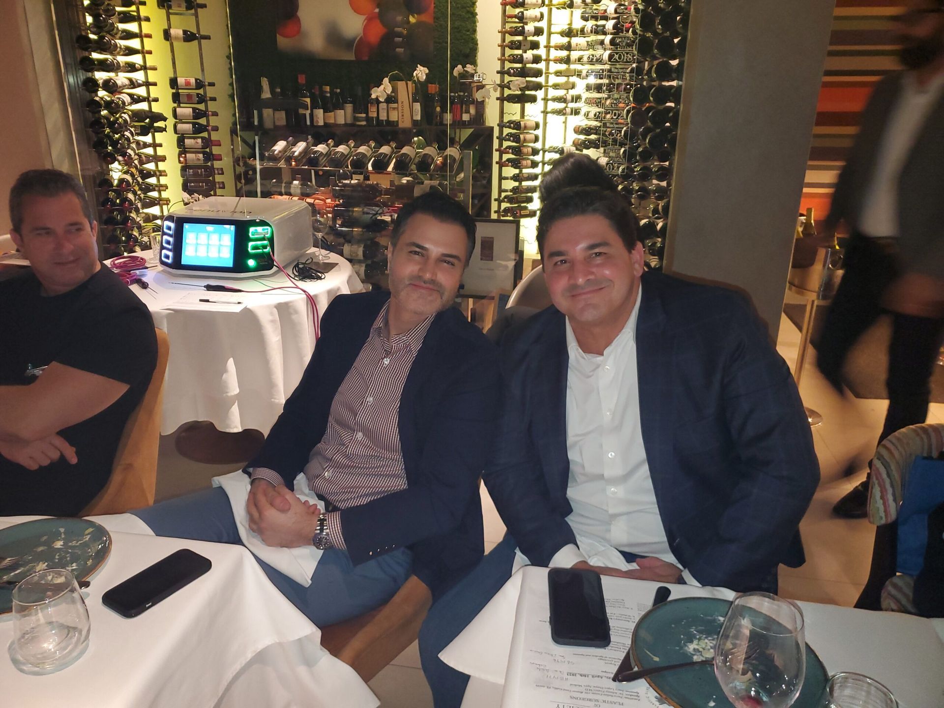 Three men are sitting at a table with a laptop on it