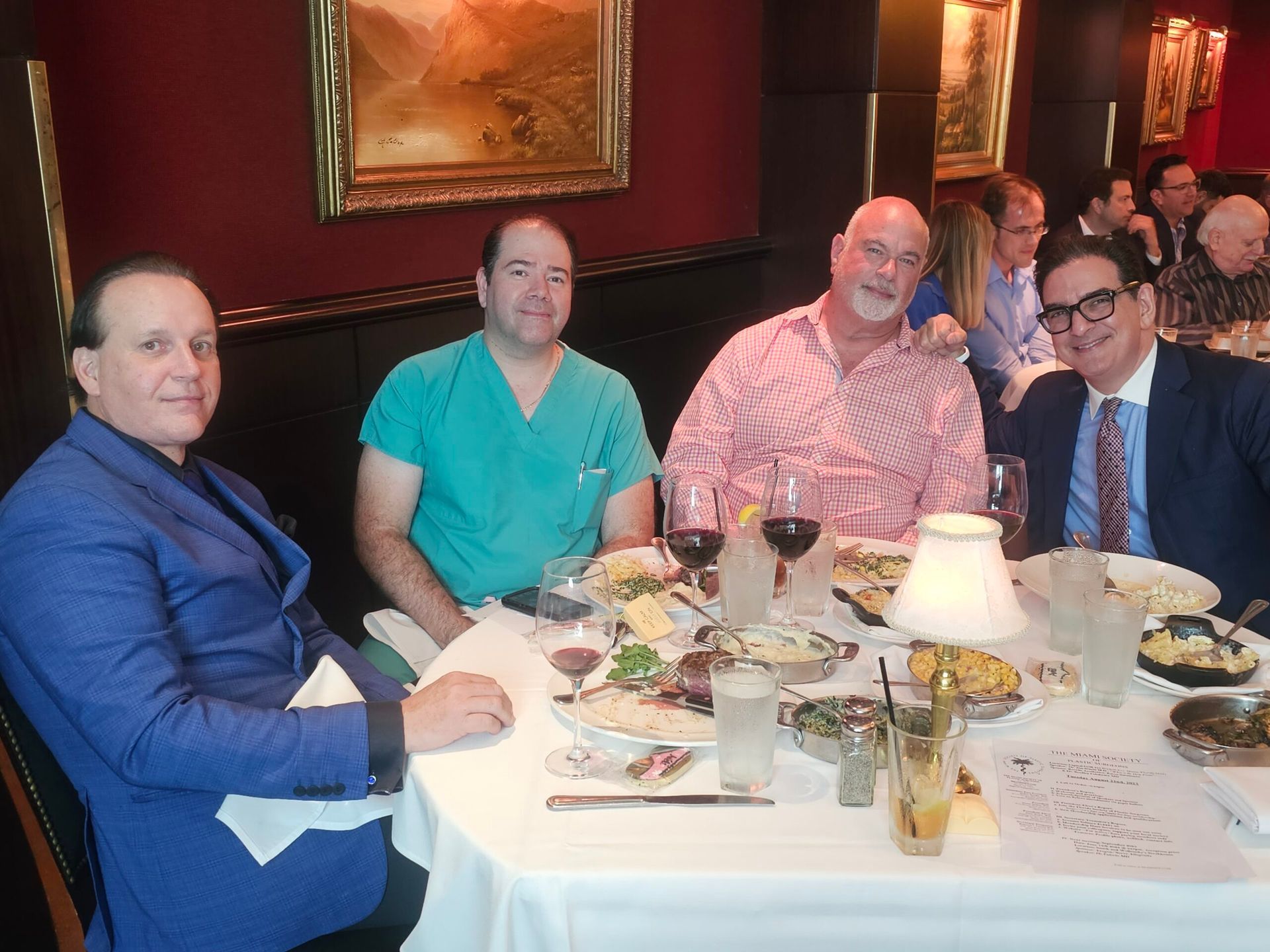 A group of men are sitting at a table with plates of food and wine glasses.