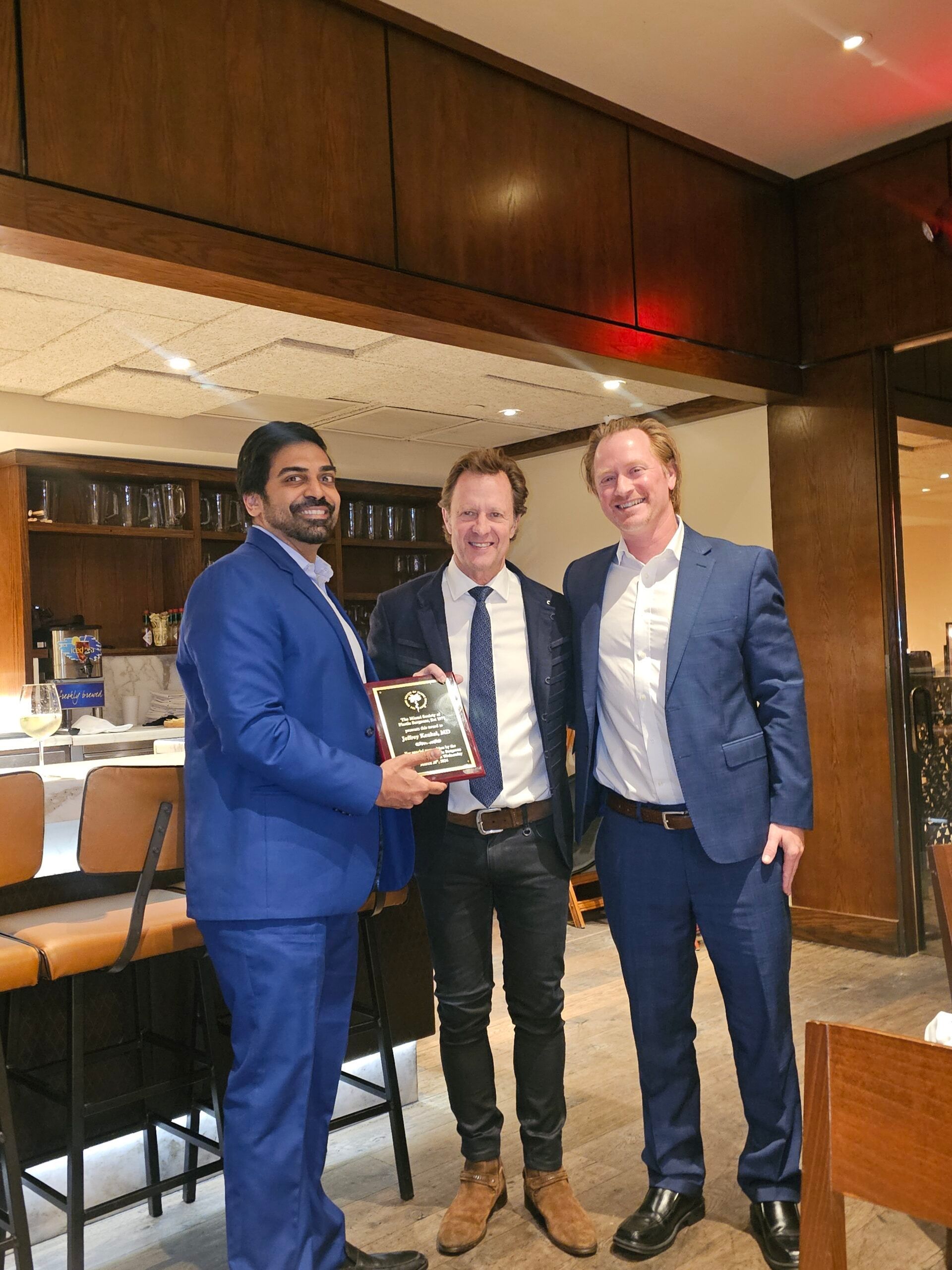 Three men in suits and ties are posing for a picture in a restaurant.