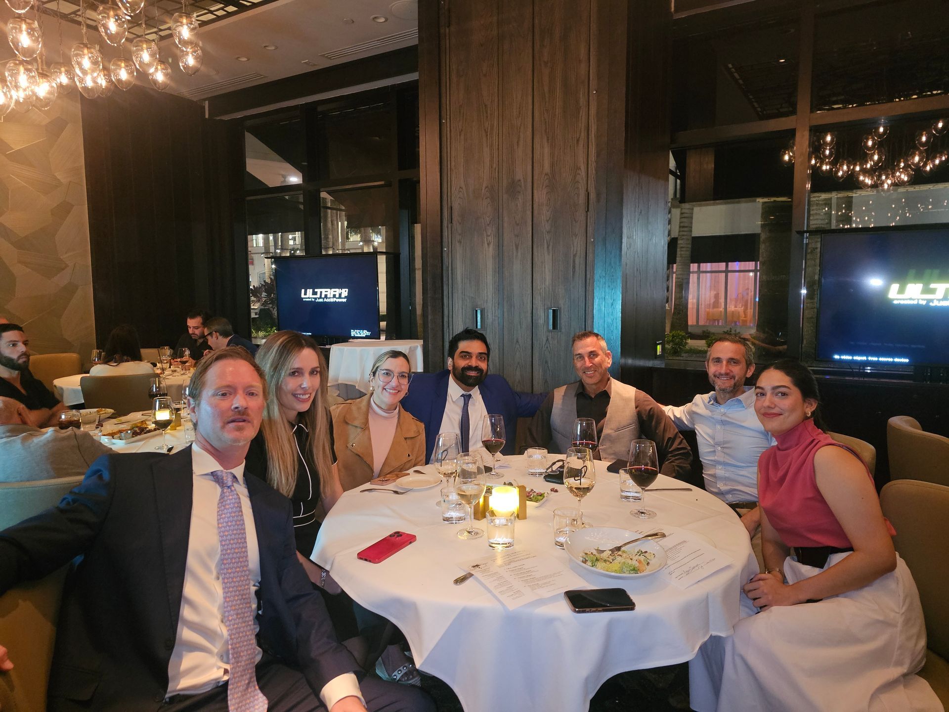 A group of people are posing for a picture at a table in a restaurant.