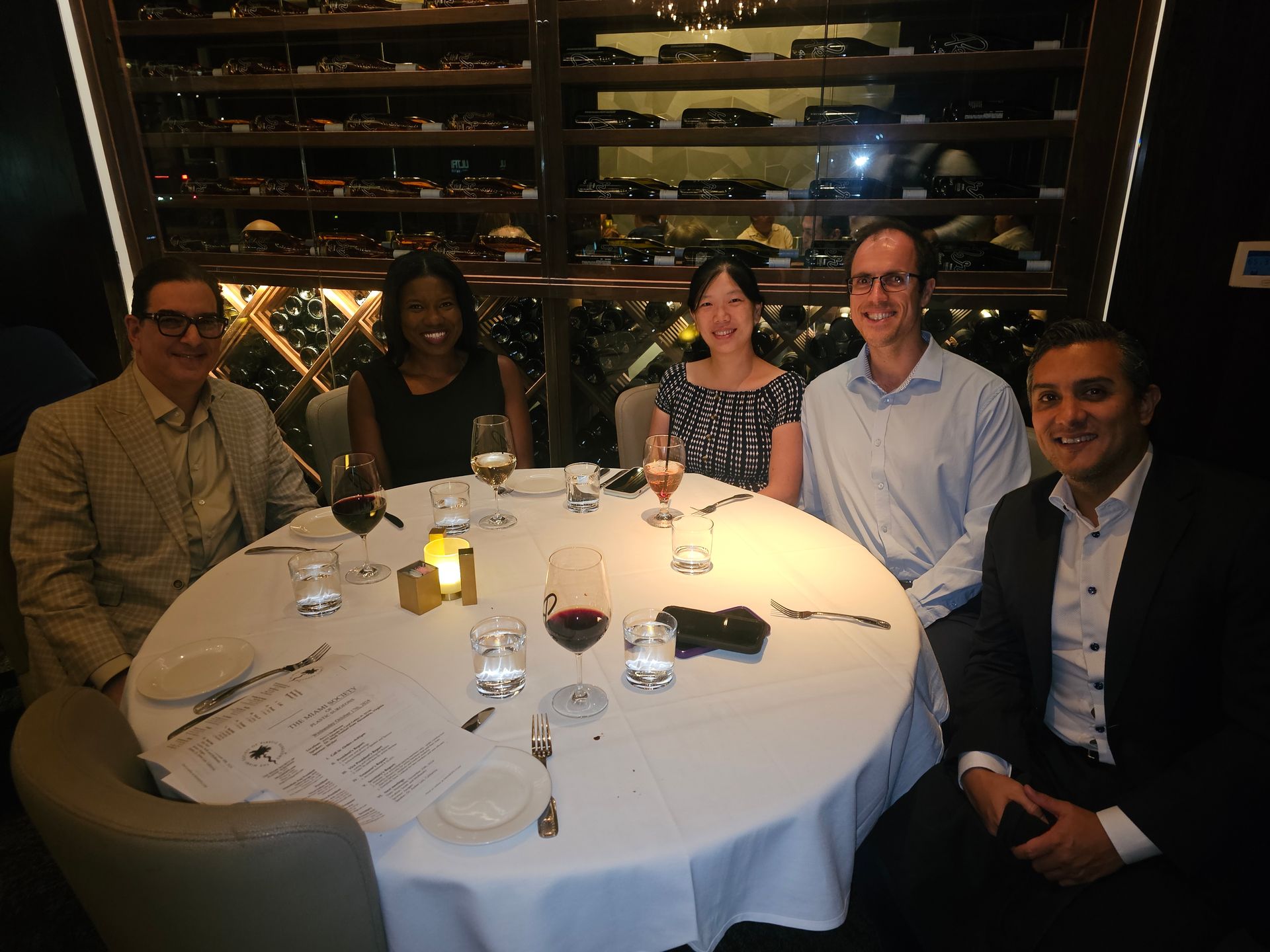 A group of people are sitting around a table with wine glasses