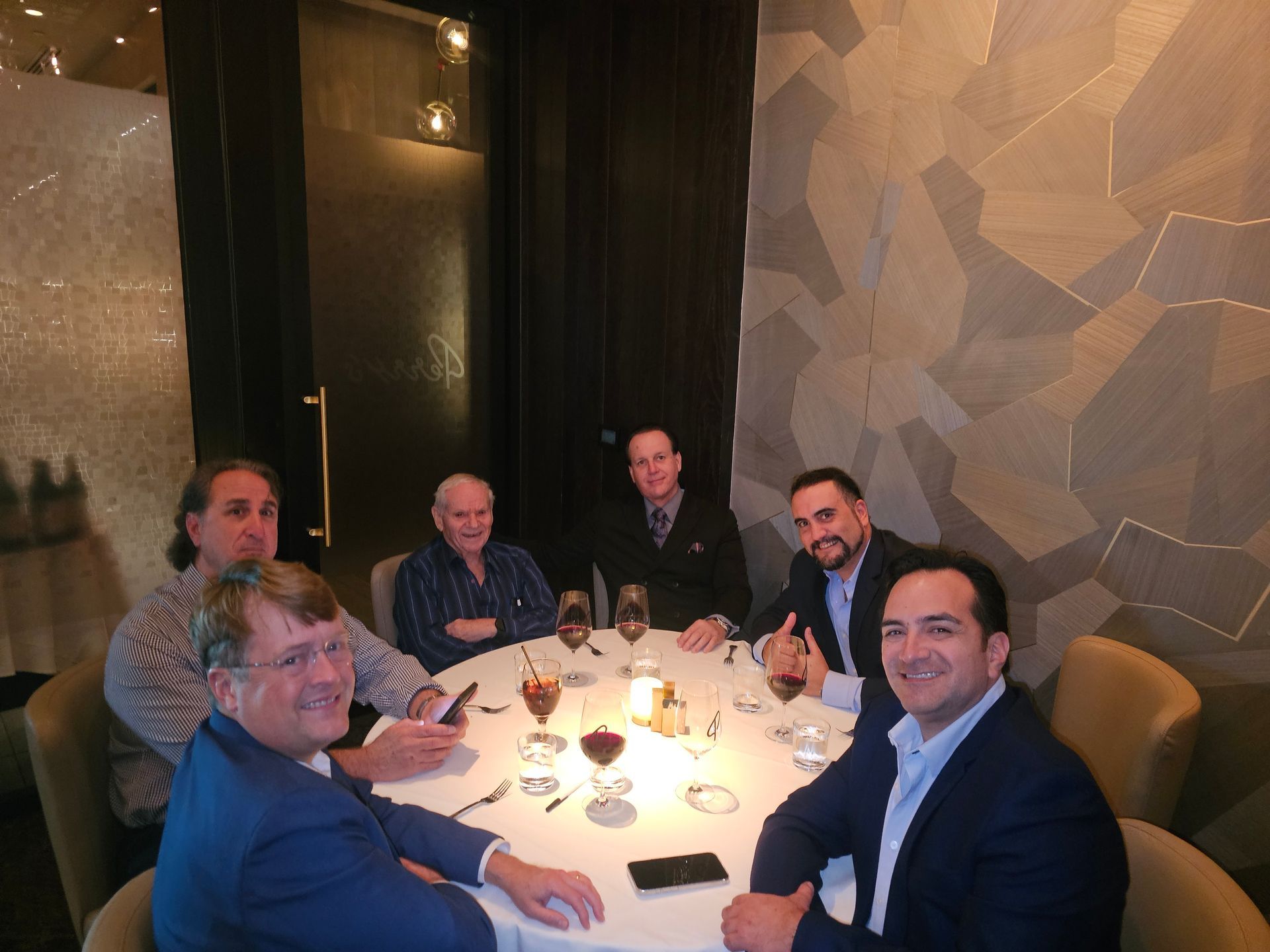 A group of men are sitting around a table with wine glasses