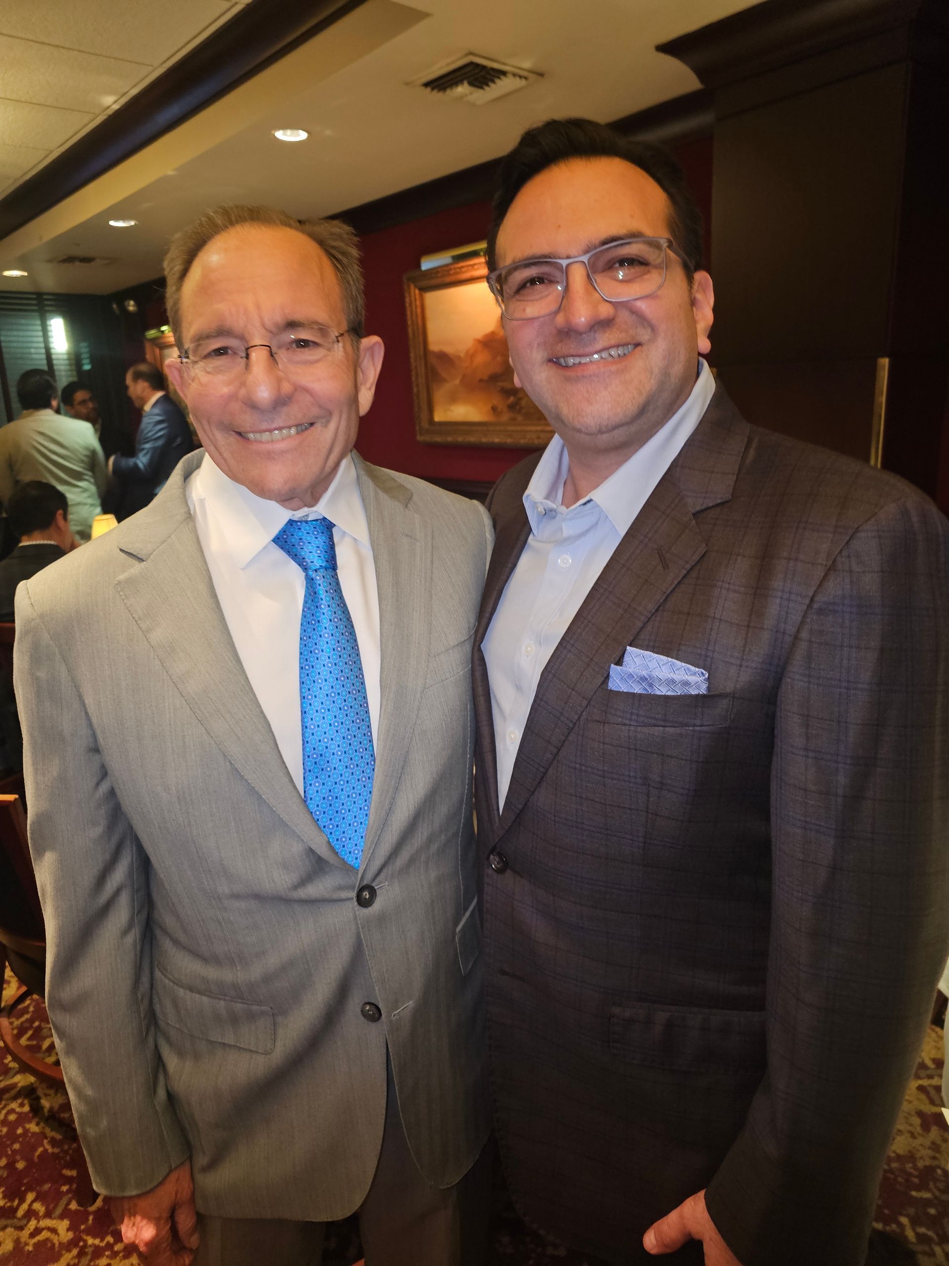 Two men in suits and ties pose for a picture
