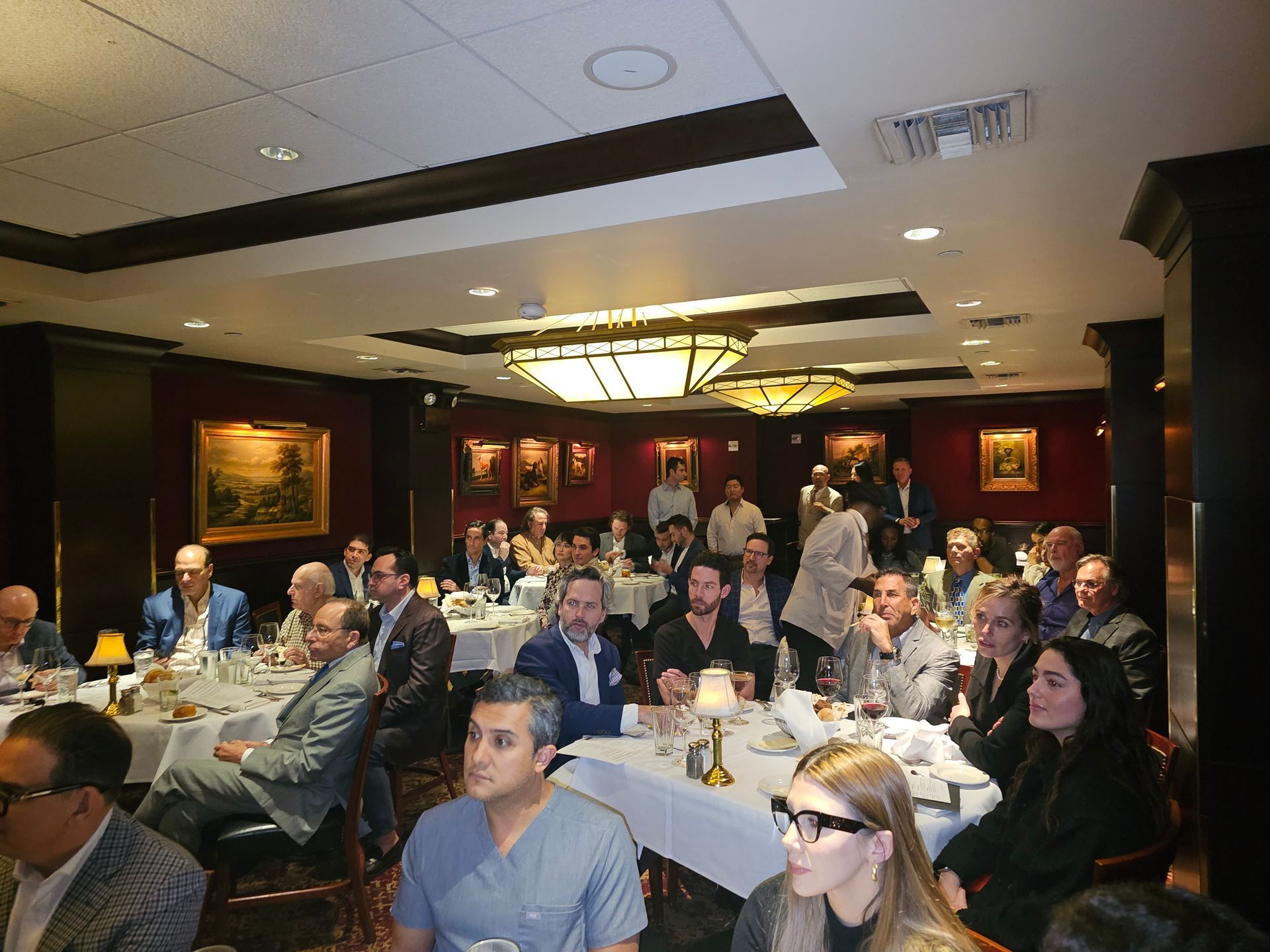 A large group of people are sitting at tables in a large room.