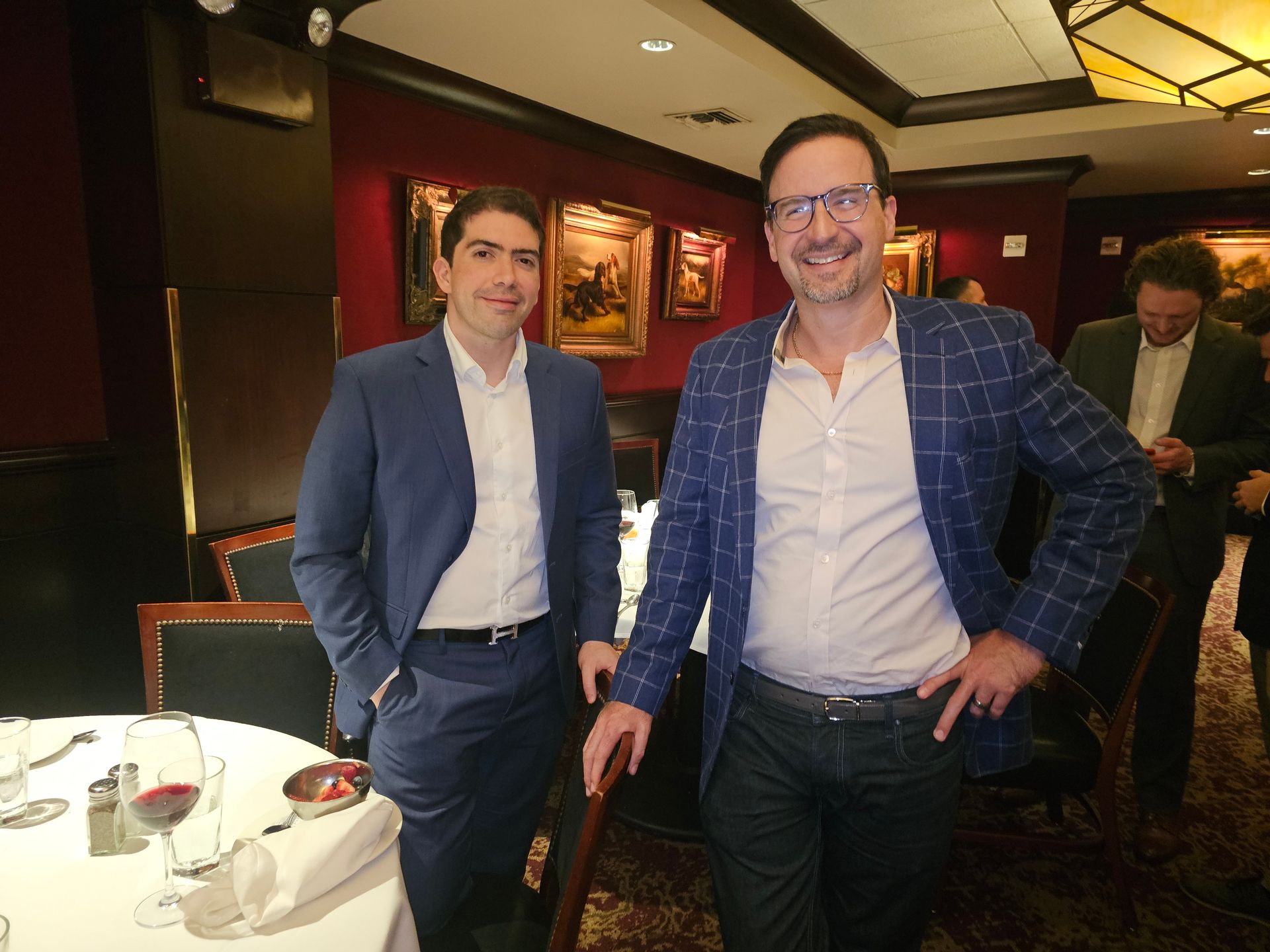 Two men in suits are posing for a picture in a restaurant