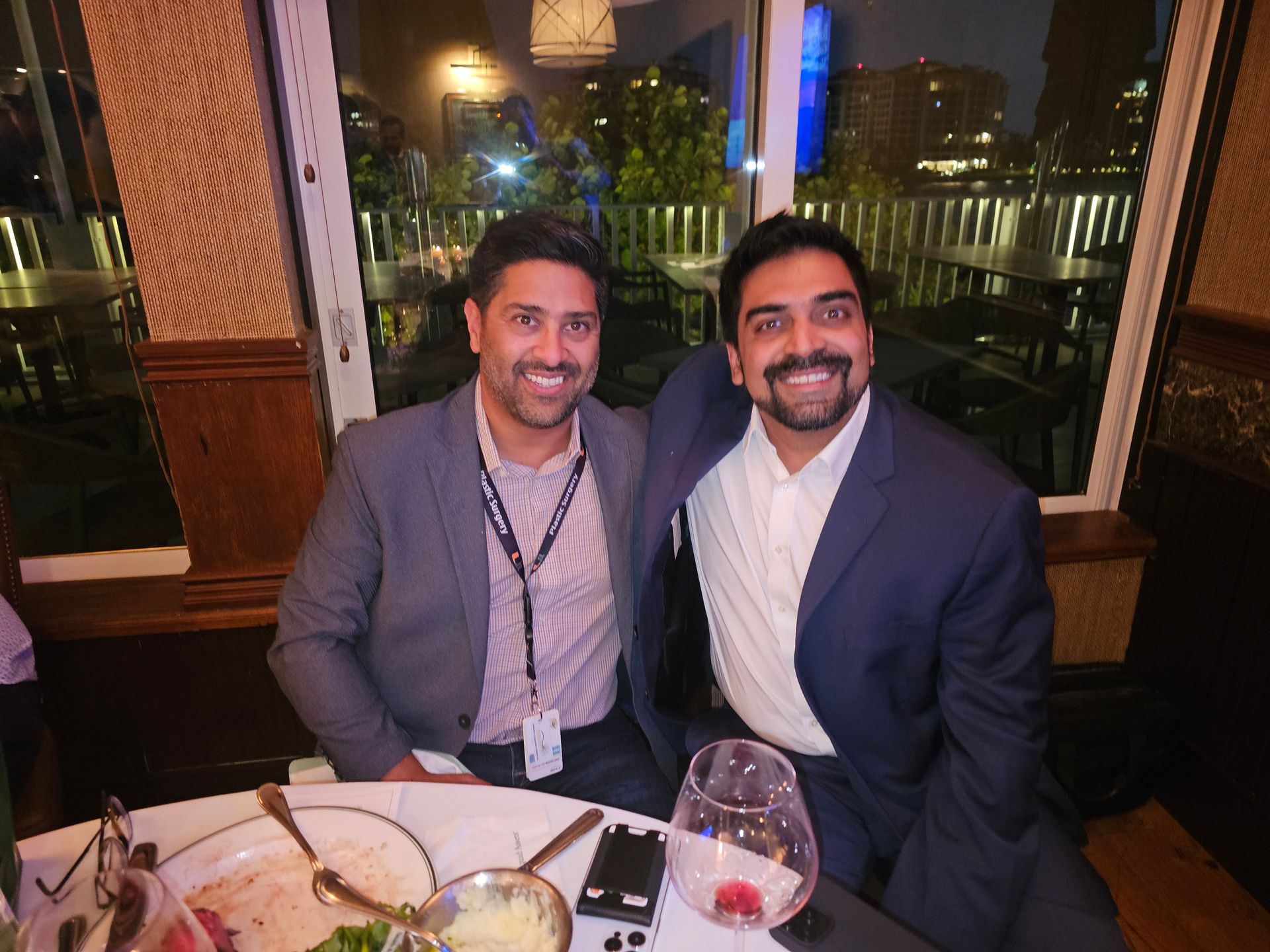 Two men are posing for a picture while sitting at a table