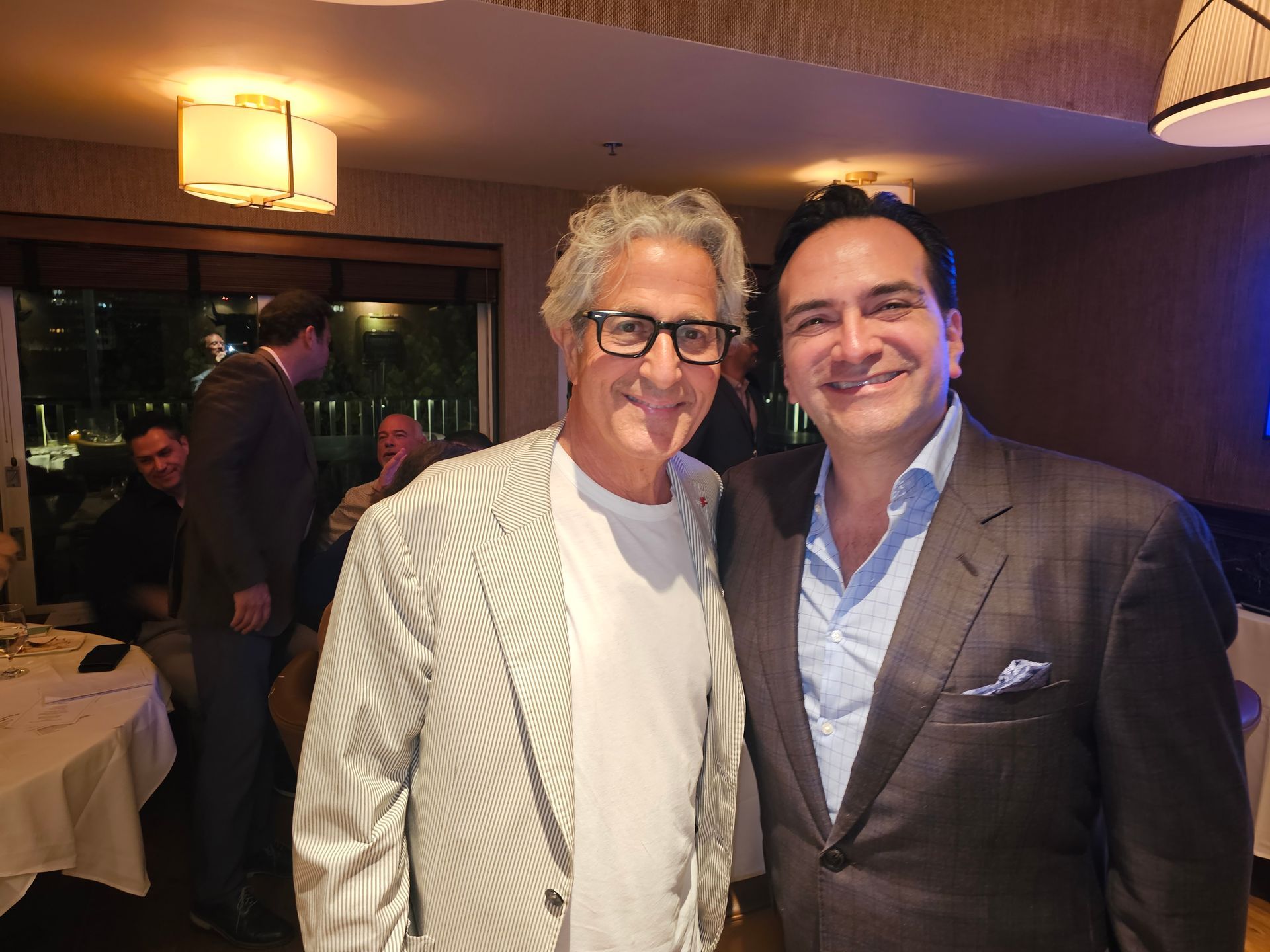 Two men in suits are posing for a picture in a room.