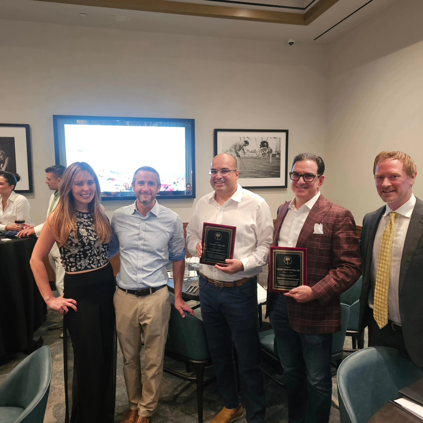 A group of people are standing in a room holding plaques.