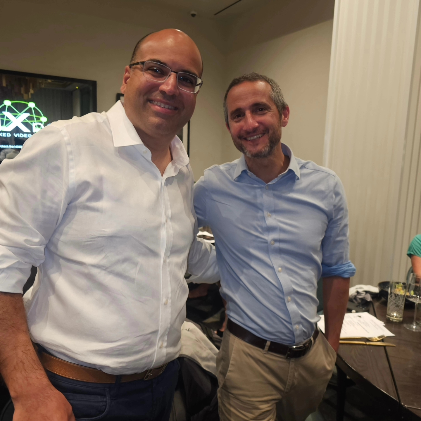 Two men are posing for a picture in front of a sign that says exit