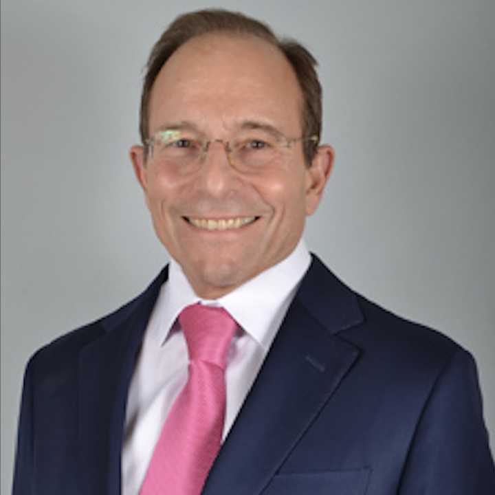 A man in a suit and pink tie smiles for the camera