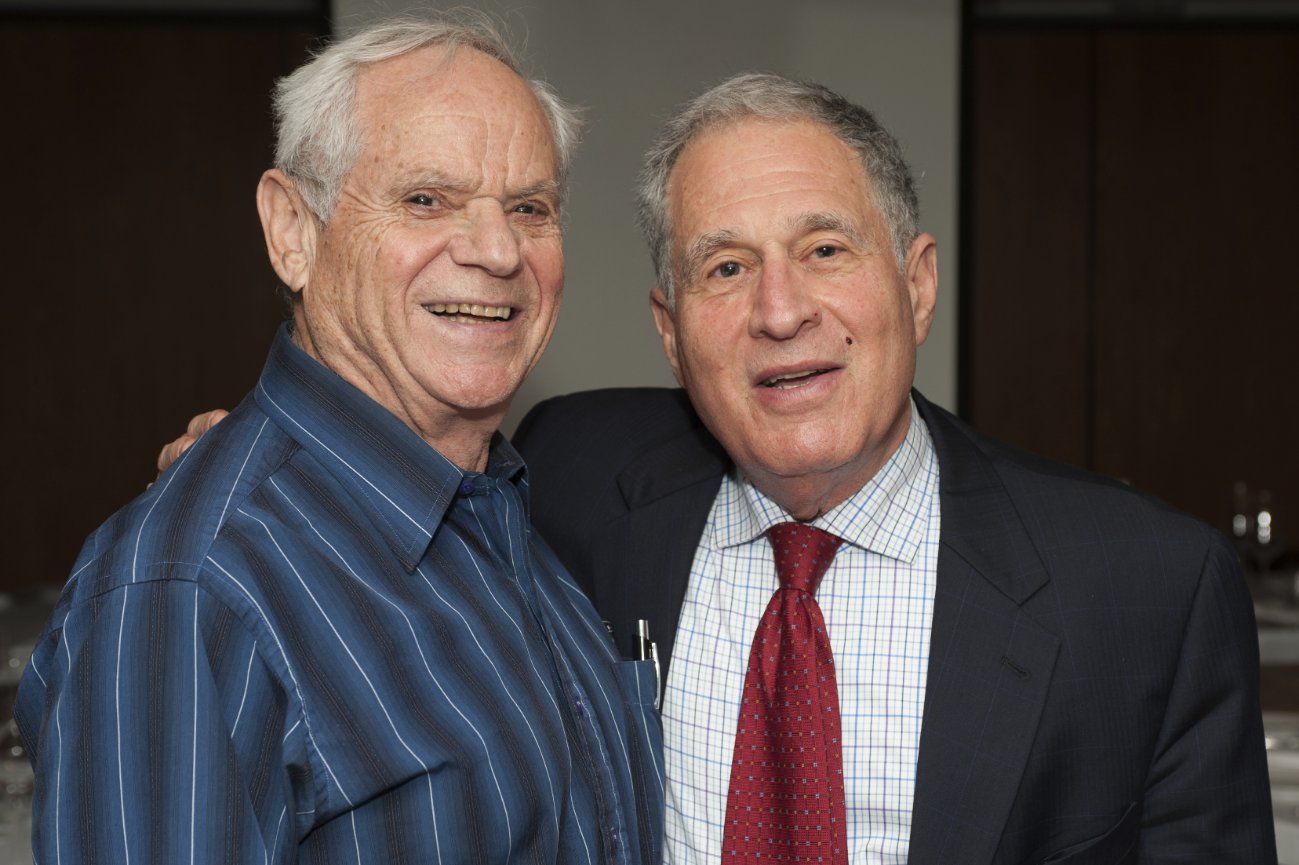 Two men in suits and ties are posing for a picture.