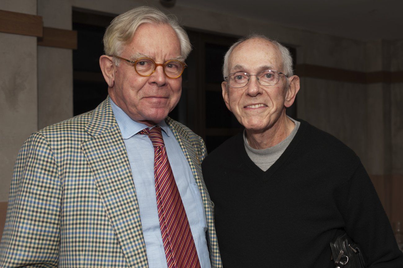 Two men in suits and ties pose for a picture
