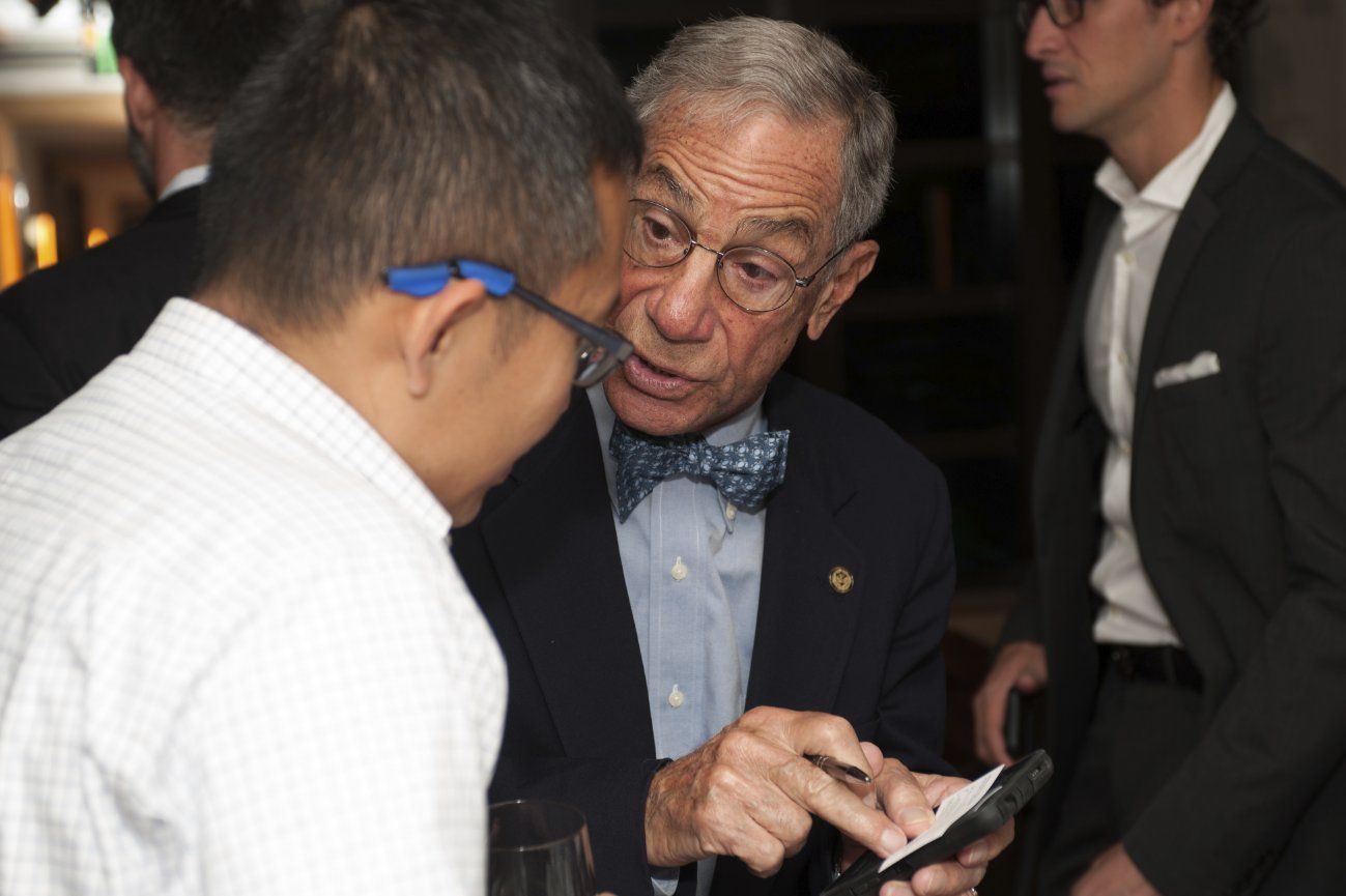A man in a suit and bow tie is talking to another man