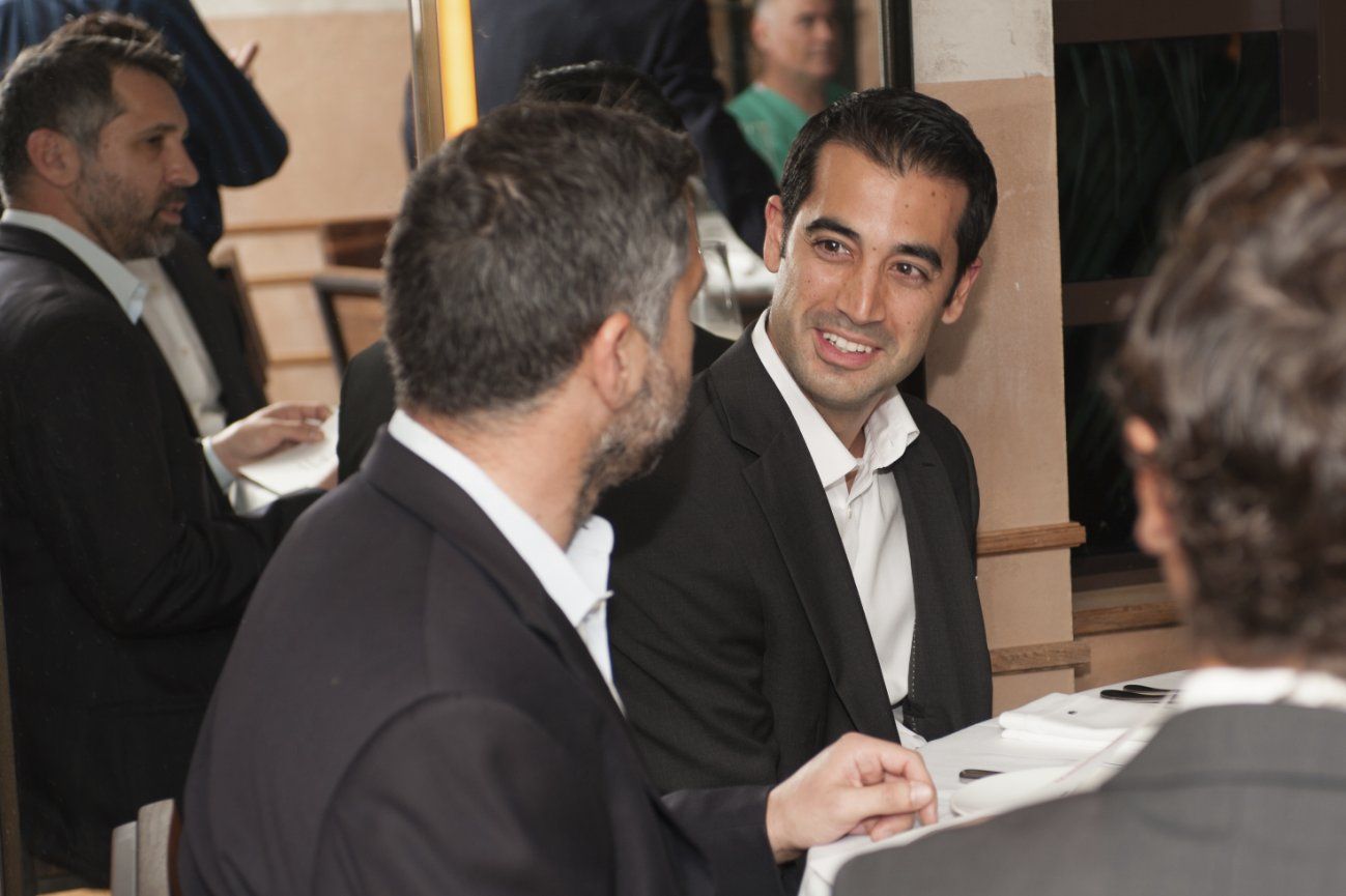 A group of men are sitting at a table talking to each other