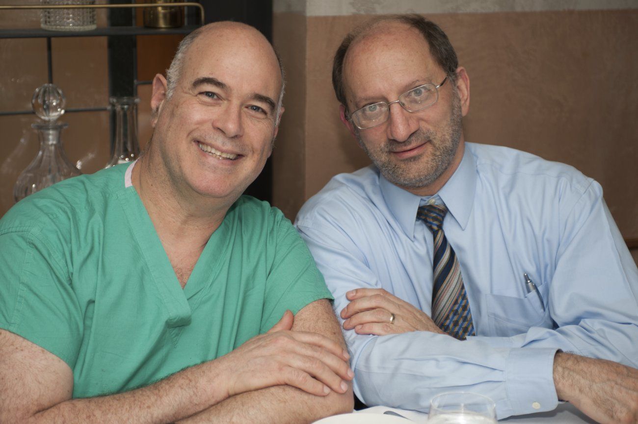 Two men in scrubs and ties are posing for a picture