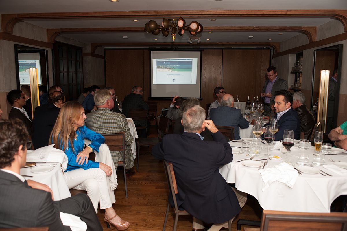 A group of people are sitting at tables in a room watching a presentation.