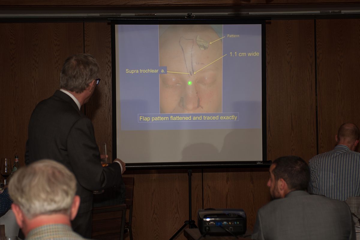A group of men are sitting in front of a projector screen.