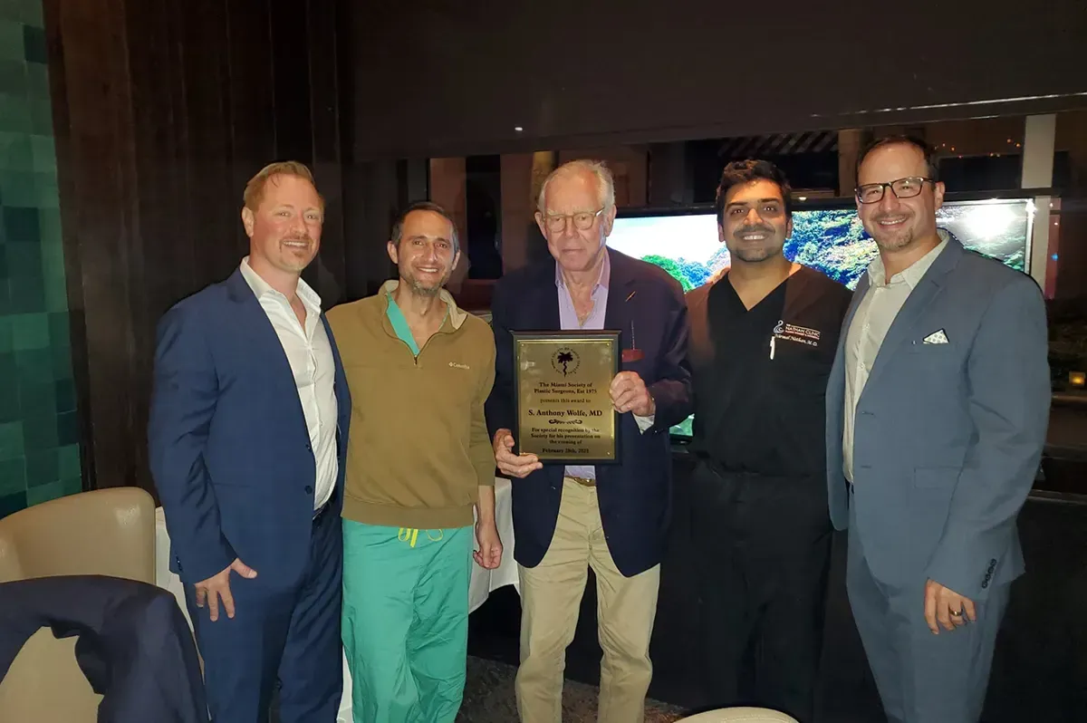 A group of men are posing for a picture and one of them is holding a plaque.