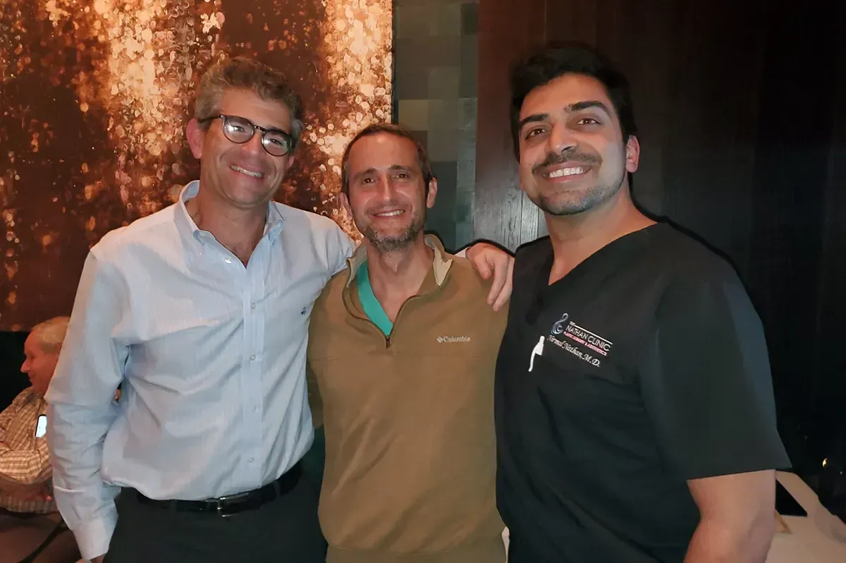 Three men posing for a picture with one wearing a shirt that says columbia