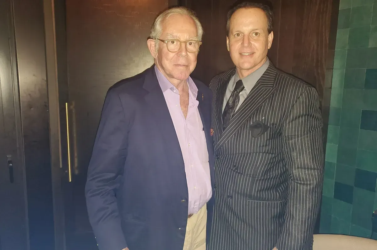 Two men in suits are posing for a picture together.