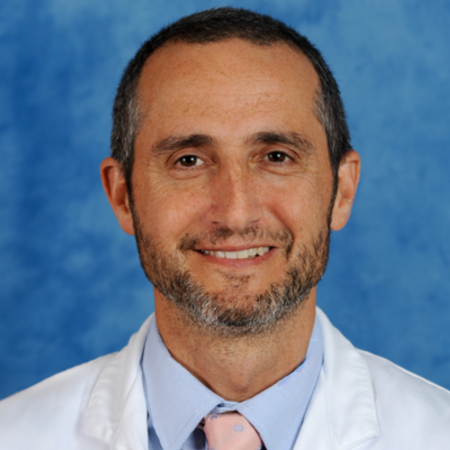 A man with a beard wearing a white lab coat and a pink tie