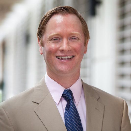 A man in a suit and tie is smiling for the camera.