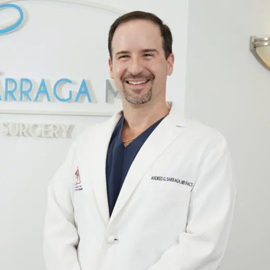 A man in a lab coat is smiling in front of a sign that says surgery