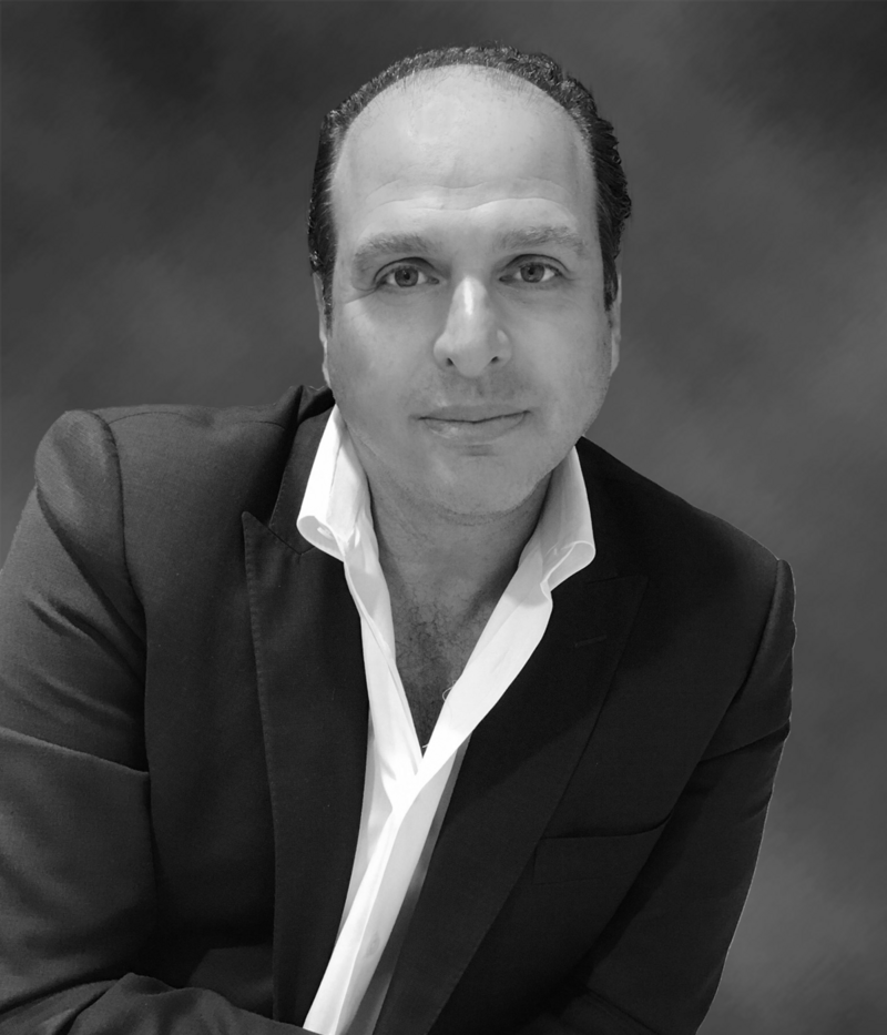 A man in a suit and white shirt is looking at the camera