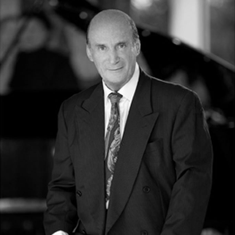 A man in a suit and tie is standing in front of a piano