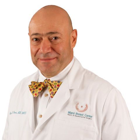 A bald man wearing a white lab coat and a bow tie