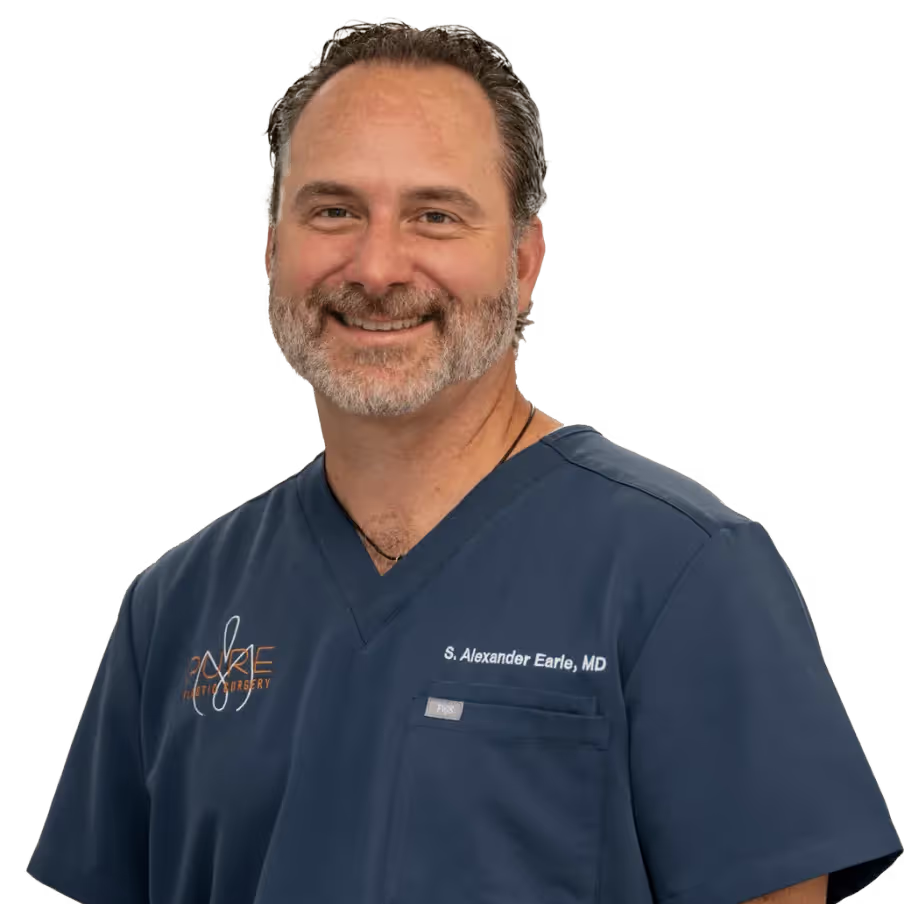 A man with a beard is wearing a blue scrub top and smiling.