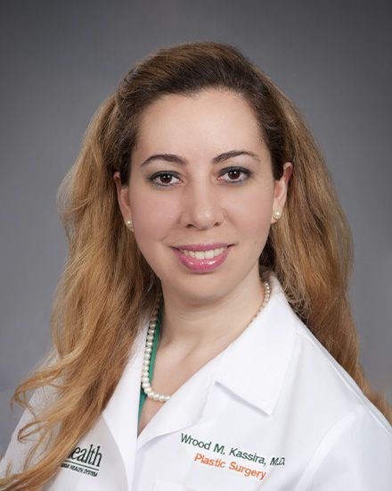 A woman in a white lab coat is smiling for the camera