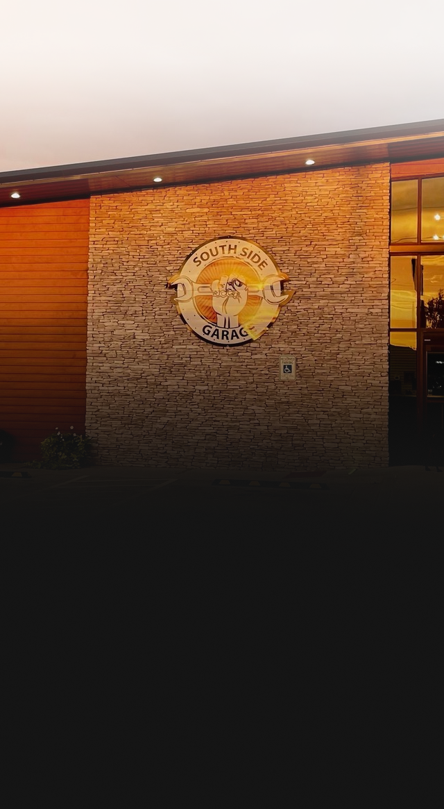 Building exterior with sign; stone and wood facade, sunset light | The SouthSide Garage