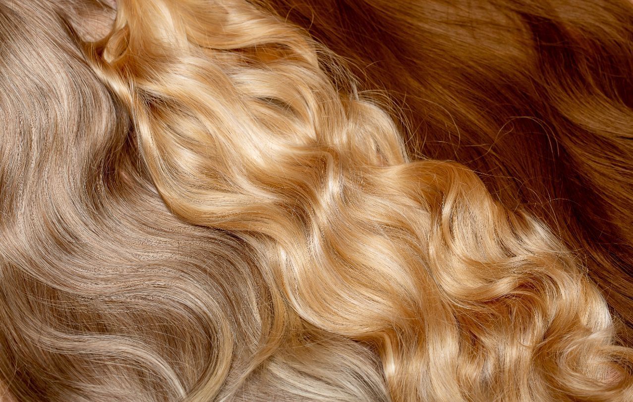 Close-up of wavy strands of light brown, golden blonde, and dark brown hair.