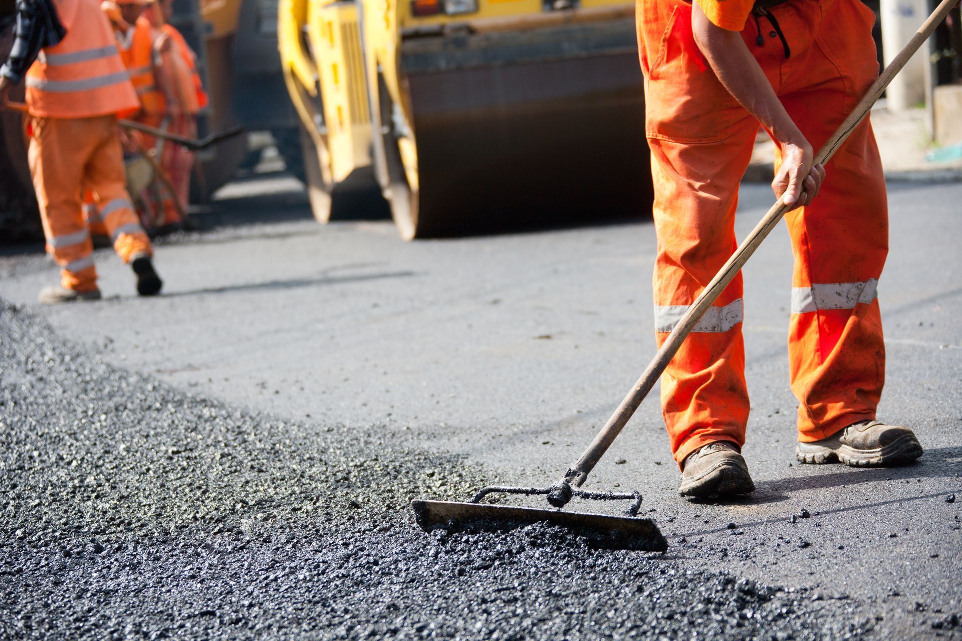 Close-up of industrial asphalt contractors working on road construction